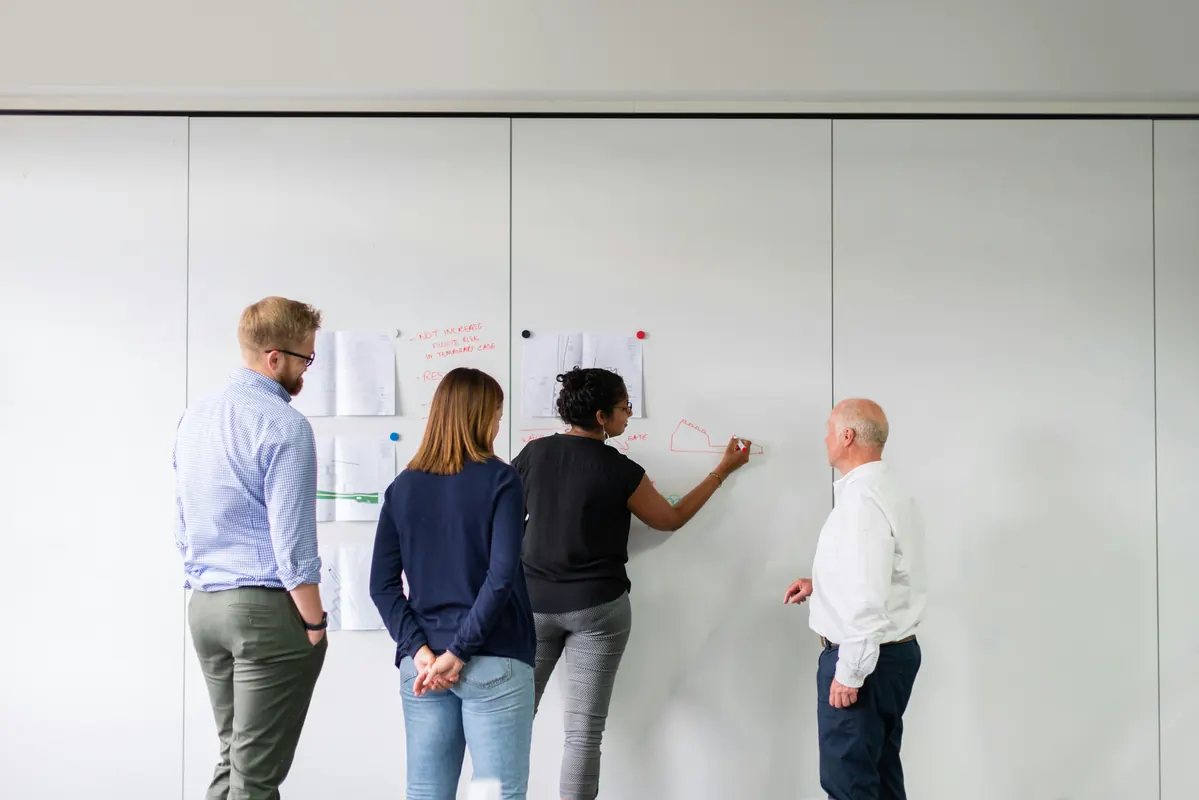 Engineers discussing ideas together at a whiteboard