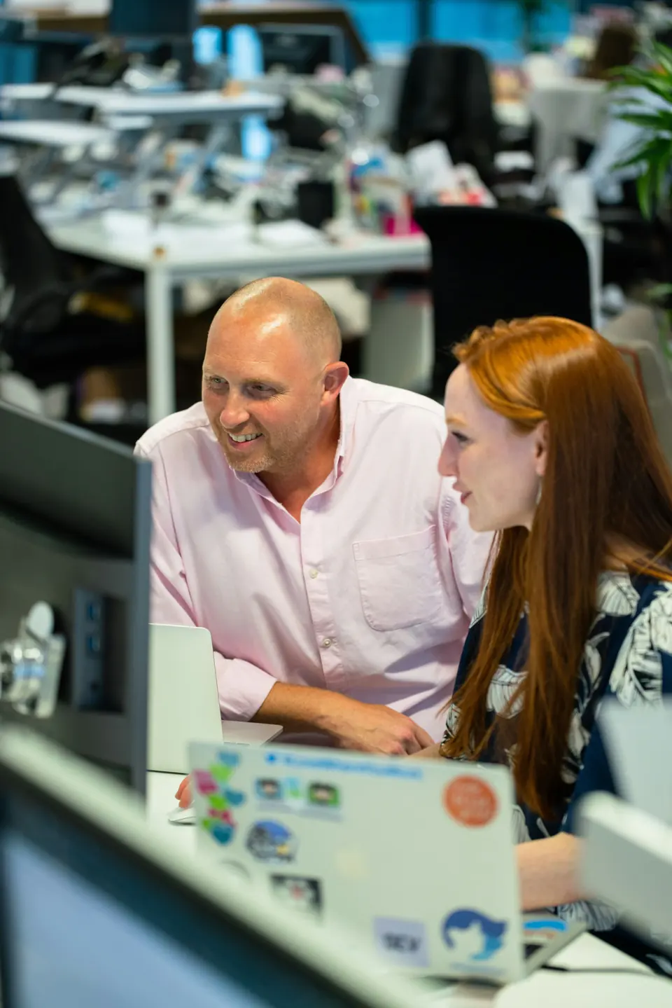 Two professionals working together at a computer in an office