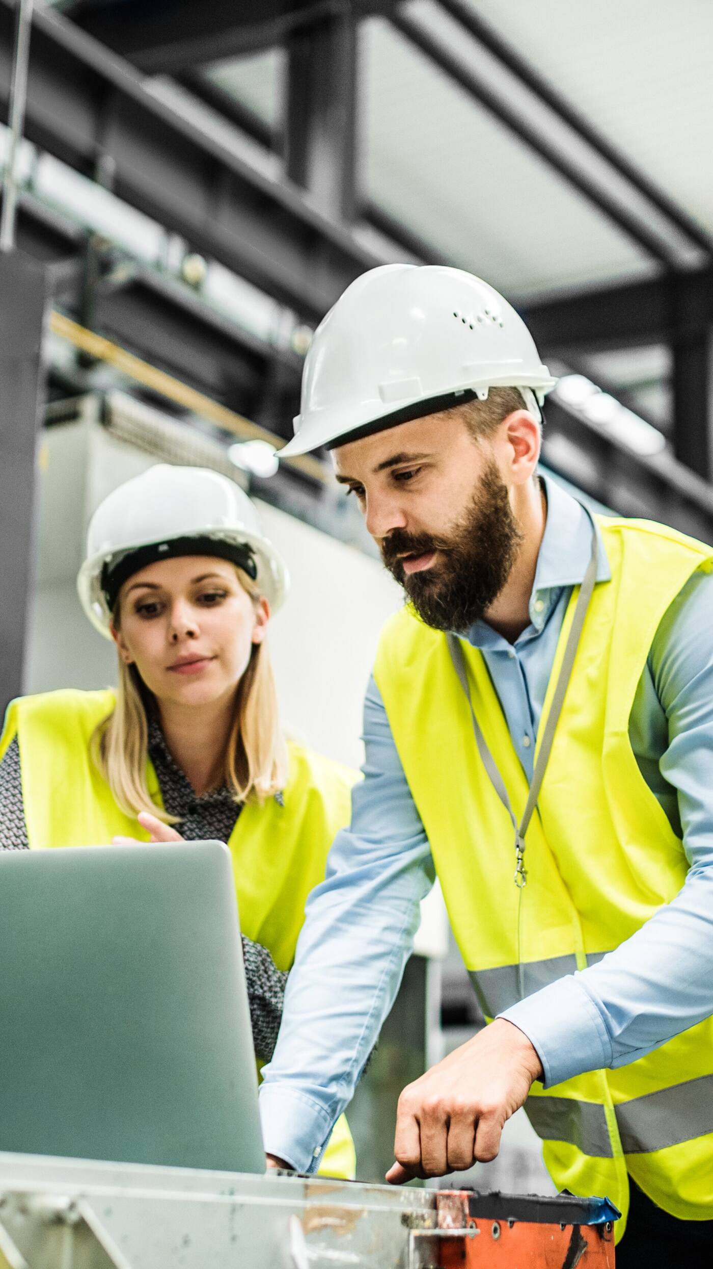 Engineers reviewing plans on laptop in industrial facility
